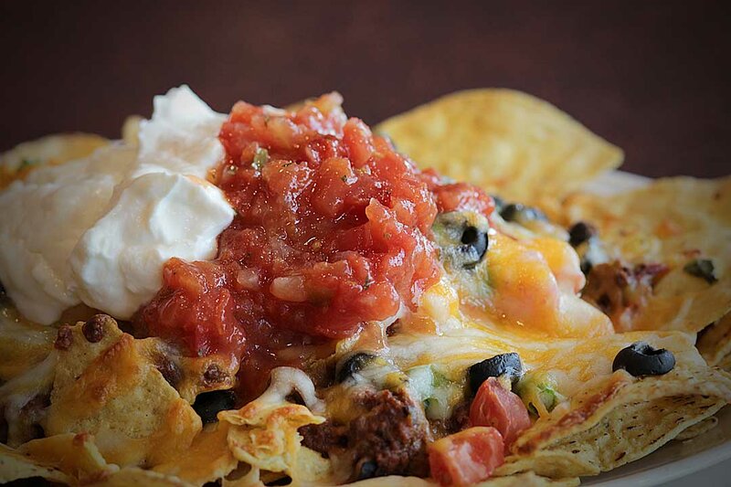 Close up view of nachos topped with salsa and sour cream